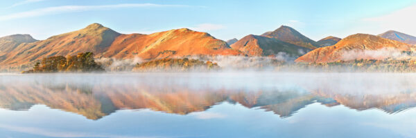 Catbells Ridge viewed from Friars Crag, beautiful autumn colours with a slight haze hovering over Derwentwater all of which is reflected in the shimmering lake beneath.