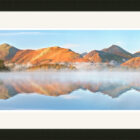 Catbells Ridge viewed from Friars Crag. Beautiful autumn colours with a slight haze hovering over Derwentwater all of which is reflected in the shimmering lake beneath.