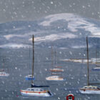 Lake District art print No Sailing Today by local artist Jeff Sudders. A winter scene with a long jetty covered in white snow in the foreground, few yachts on the Lake Windermere in the Lake District and some mountains in the background; the small snowflakes are falling down across the print.