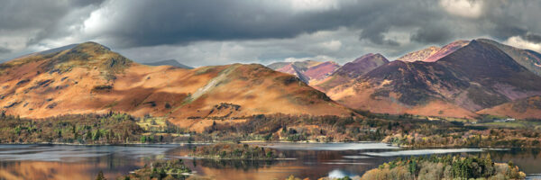 view across derwentwater from walla crag featuring catbells in the sun with newlands valley behind