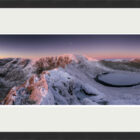 Print by Lake District Photographer Nathan Buckley Winter on Striding Edge featuring an icy and snowy Red Tarn and Helvellyn in a pink first light glow