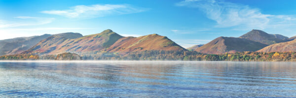 an incredible view from the lake edge of derwent water featuring catbells and the newlands fells of causey pike and maiden moor with a sunlit mountain and bright blue water