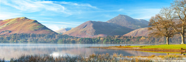winter lakeside view of derwentwater with catbells and causey pike in the background, a steamy lake and frosty grasses in the foreground