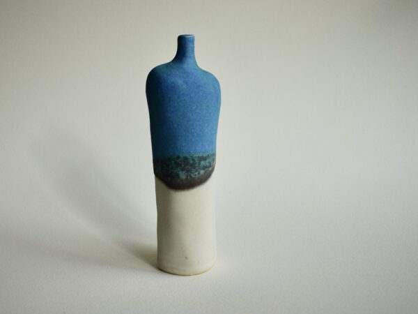 Bottle by Kirsti Hannah Brown. Slender stoneware bottle with shoulders and a neck to suggest a figurative form. Turquoise and white glazes crate a horizon line where they overlap.