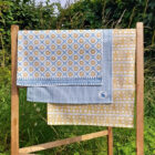 Sunburst 100% organic cotton tea towel by Miller Honeyman in blue and yellow with coordinating patterned edges.