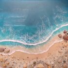 Lake District art gallery. Breaking Waves by Tamsin Pease. A resin mixed media piece with mica powders and acrylic inks. Real sand and pebbles used to create an aerial shoreline