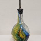 Handmade glass oil pourer. Rounded bottle bottom. Kingfisher feather colours, yellow, blue, red and greens.
