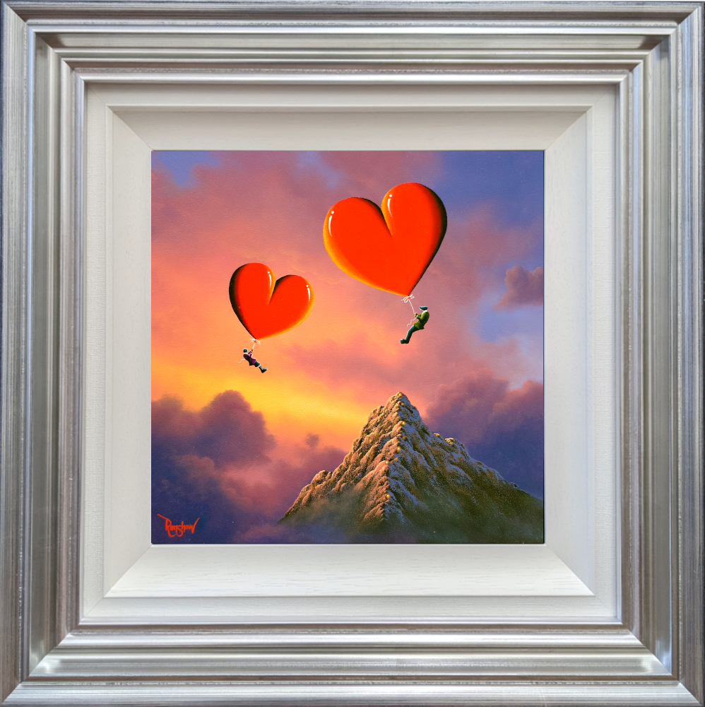 Lake District original art by David Renshaw featuring ted and doris with heart balloons in front of a large mountain and sunset. In blue silver frame.