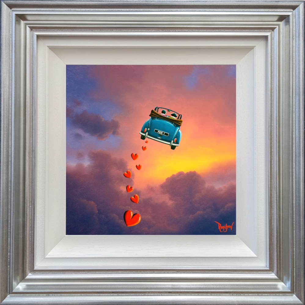 lake district art romantic original oil painting by david renshaw. featuring Ted and Doris in a blue convertible flying into a dreamy pink sunset-followed by a trail of hearts. Displayed in a silver blue frame.