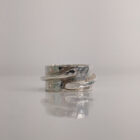 A chunky silver ring with a thin band detail layered over a hammered surface. Approximately 0.75” in diameter.