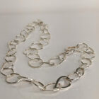 A handcrafted silver chain featuring a flowing arrangement of oval and raindrop shaped motifs. Chain is approximately 8“ in length.