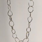 A handcrafted silver chain featuring a flowing arrangement of oval and raindrop shaped motifs. Chain is approximately 8“ in length.