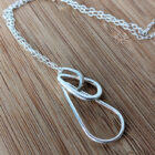 A handcrafted silver necklace showcasing three intertwined raindrop pendants. Chain is approximately 9“in length. Raindrop pendants approximately 1”.