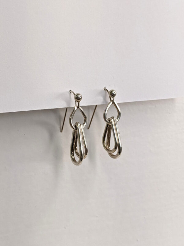 Handcrafted silver earrings featuring a trio of raindrop pendants. Approximately 1” in length. Side view.
