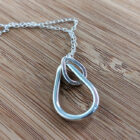 A handcrafted silver necklace showcasing two interlinked raindrop pendants. Chain is approximately 9“in length. Raindrop pendants approximately 1.25”.
