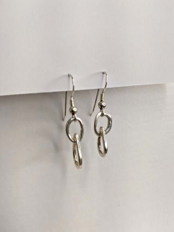 Handcrafted silver earrings featuring a delicate raindrop pendant. Approximately 1.75” in length. Side view.