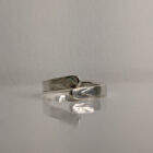 A silver wrap ring featuring a printed raindrop design. Pointed edge. Approximately 0.75” in diameter. Handmade by Helen Wiseman