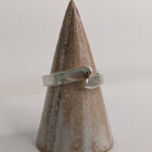 A silver wrap ring featuring a printed raindrop design. Pointed edge. Approximately 0.75” in diameter. Handmade by Helen Wiseman