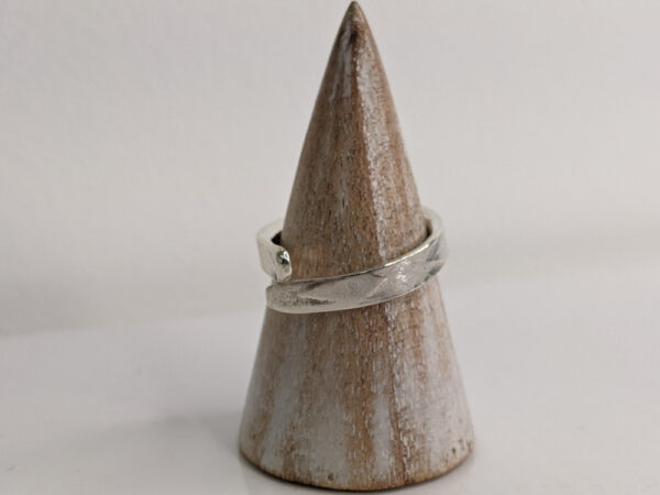 A silver wrap ring featuring a printed raindrop design. Pointed edge. Approximately 0.75” in diameter. Handmade by Helen Wiseman