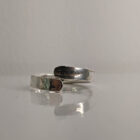A silver wrap ring featuring a printed raindrop design. Rounded edge. Approximately 0.75” in diameter. Handmade by Helen Wiseman