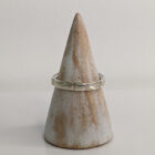 A thin silver ring with small indents across the band. Approximately 0.7” in diameter..Handmade by Helen Wiseman. Displayed on a wooden ring stand.