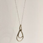 A handcrafted silver necklace showcasing three raindrop pendants with a hammered texture. Chain is approximately 9“in length. Raindrop pendants approximately 1.25”. White background.