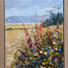 Oil painting of a wildflower-filled field under a pale blue sky. Red and blue flowers bloom in the foreground, with tall white flower clusters rising above them. Golden grasses stretch into the distance toward soft blue hills and a line of dark trees, painted with visible, textured brushstrokes. Displayed in a light oak ray frame.