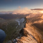 Print by Lake District Photographer Nathan Buckley. Sunrise over striding edge. view from helvellyn of misty fell red tarn ullswater in winter snow