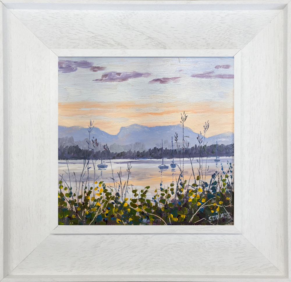 lake district art original oil painting by local artist Jeff Sudders featuring a soft evening sunset set across lake Windermere sailboats floating in the water and flowers in the foreground. Displayed in a white frame.