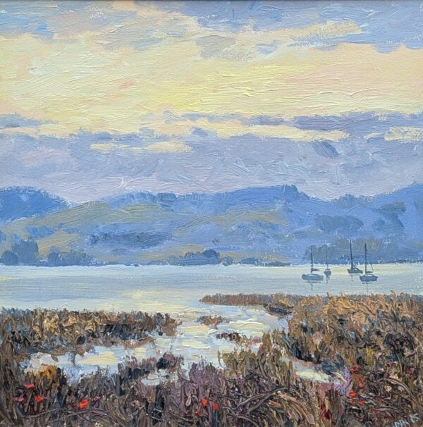 A soft, impressionistic landscape painting showing a calm lake at sunset. Three small sailboats rest on still water, reflecting the pastel sky. In the foreground, tall reeds and marsh plants in earthy browns and purples frame the scene. Rolling blue‑green hills rise in the distance beneath a sky painted with gentle yellows, blues, and lavender tones.