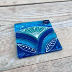 Inspired by the iconic Lotus flower this handmade coaster is made using rich expressive blue and turquoise coloured glass and finished with delicate hand-painted details.