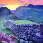 Colorful sunset over blue-green mountains, with a curved stone wall, grassy hillside, and pink wildflowers in the foreground.
