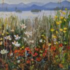 Wildflowers bloom along a lakeshore, with sailboats, wooded islands, and blue mountains in the distance.