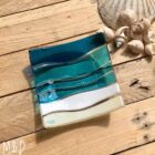 This beautiful trinket fused glass dish is made using colours of the sand and sea with additional hand-painted details made by Mother and Daughter glass.